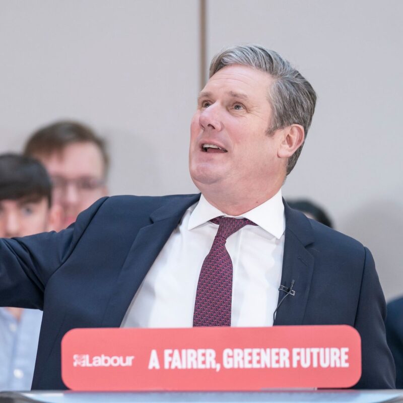 Keir Starmer stands behind a Fairer, Greener, Future sign